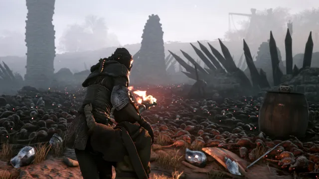 Amicia holds a burning torch at the edge of a field covered by a swarm of rats, among spiked barricades and ruined towers