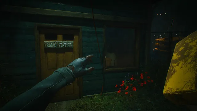 First-person view reaching toward the door of a small wooden radio station at night