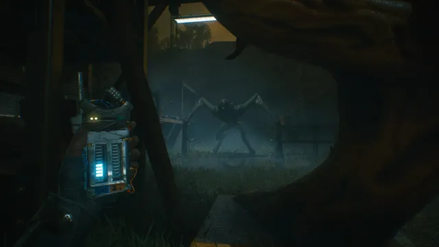 Hiding behind a fallen tree with a glowing noise meter in hand while a long-limbed creature stands in the fog beyond a fence