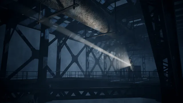 Alan Wake Remastered screenshot: Alan walks a steel walkway under a bridge, his flashlight beam cutting through the dark