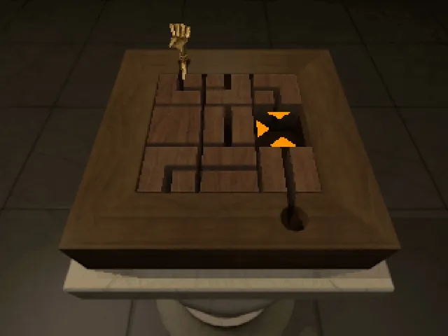 A wooden sliding block puzzle box on a table, with a doll's hand rising from one corner