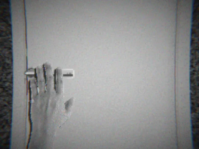 blank_01 screenshot: a pale hand pressed against a white door frame, framed by static
