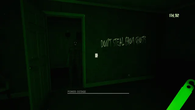 During a power outage, a dark room seen by green glow stick light with 'Don't steal from ghosts' written on the wall and a figure in the doorway