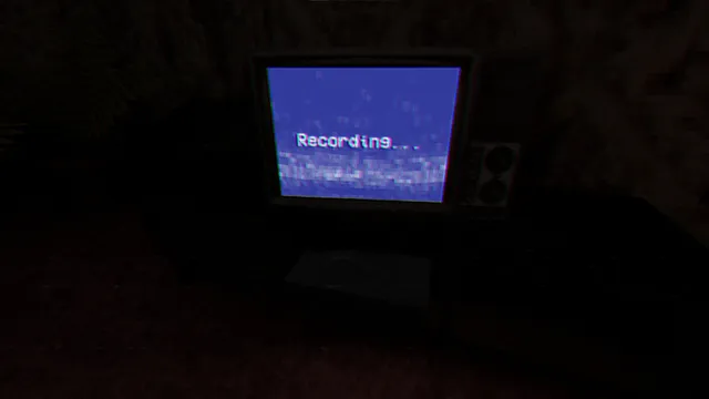 An old television in a dark room showing Recording on a blue screen, used to save progress