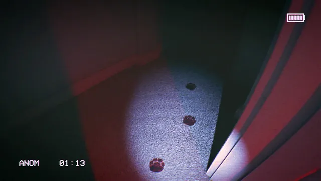 Dark paw prints lead across a carpet into a red-lit room in the flashlight beam