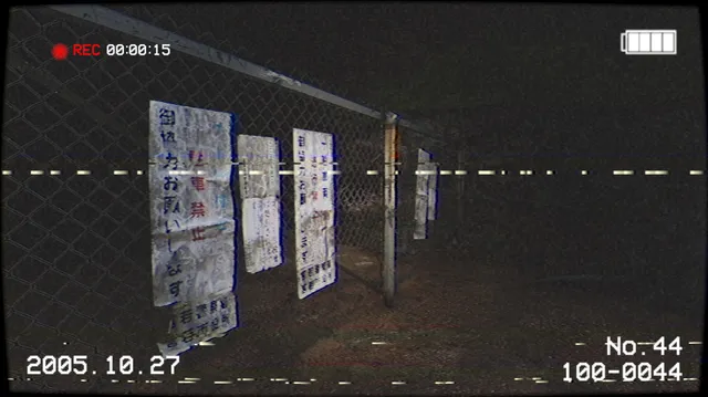 Torn Japanese warning notices hung on a chain-link fence at night