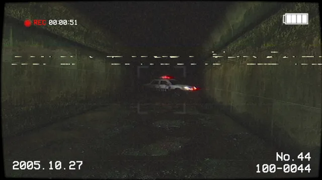 A police car with flashing lights at the far end of a dark concrete tunnel, seen through a camcorder