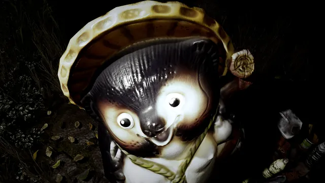 A ceramic tanuki statue lit by a flashlight beside the path in the dark
