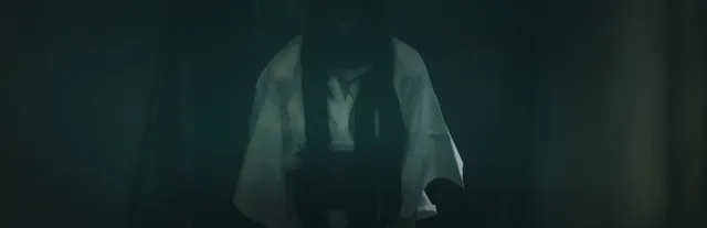 Onryo key art: a long-haired ghost in a white kimono standing bent over in a dark green room
