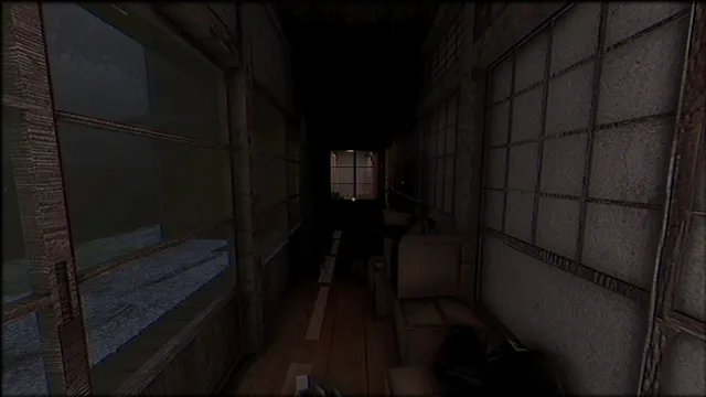 A dark corridor in the house cluttered with a sofa and boxes, a lit window at the far end