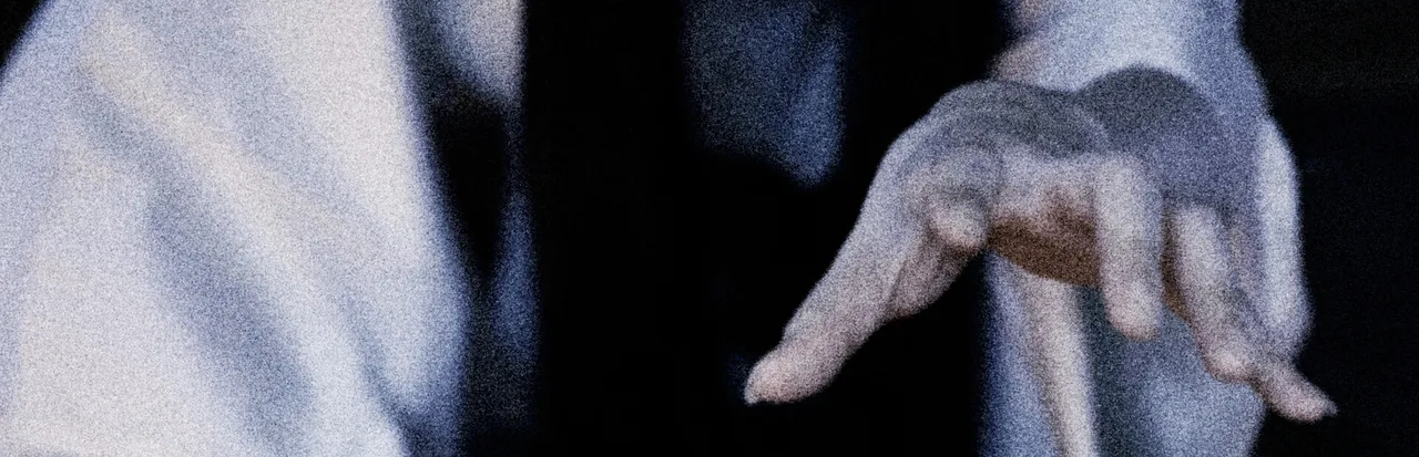 Yuki Onna key art: the pale hand of a woman in a white kimono reaching out in the dark