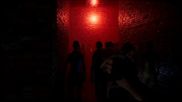 Silhouetted people in a narrow red-lit brick corridor of a nightclub