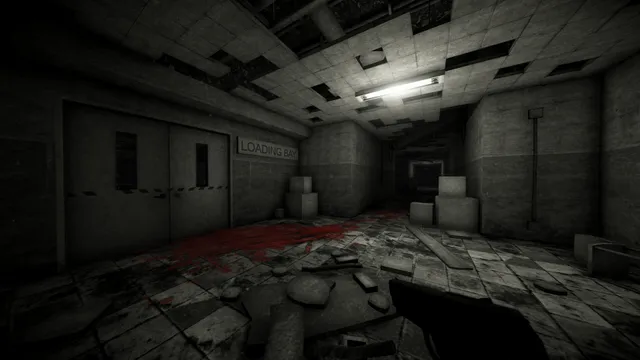 A grey, ruined corridor by the factory's loading bay, with a broken ceiling and a smear of blood across the floor