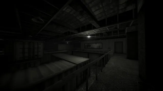 A dark factory hall seen from a walkway, with metal roofs below and a single hanging lamp