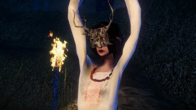 A figure in a bark mask and white embroidered shirt raises her arms beside a burning torch at night
