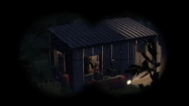 A binocular view of a small cabin in the dark woods with a light inside