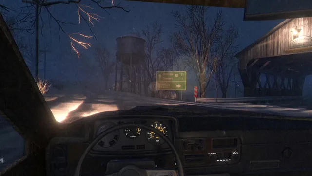 Driving a car on a snowy road at night past a water tower and a road sign