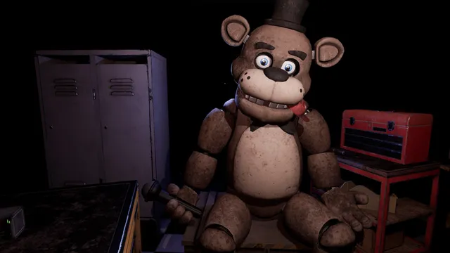 Five Nights at Freddy's: Help Wanted: Freddy Fazbear sits slumped on a workbench in a dark repair room, holding a microphone, beside lockers and a red toolbox
