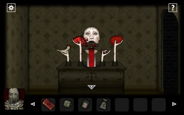 A pale mask surrounded by severed hands holding a heart, a brain and an eye on a dresser