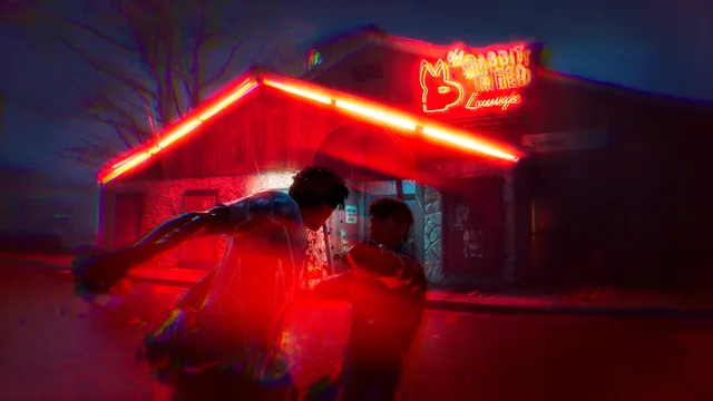Halloween: The Game screenshot: a player runs past a bar's glowing red neon sign at night
