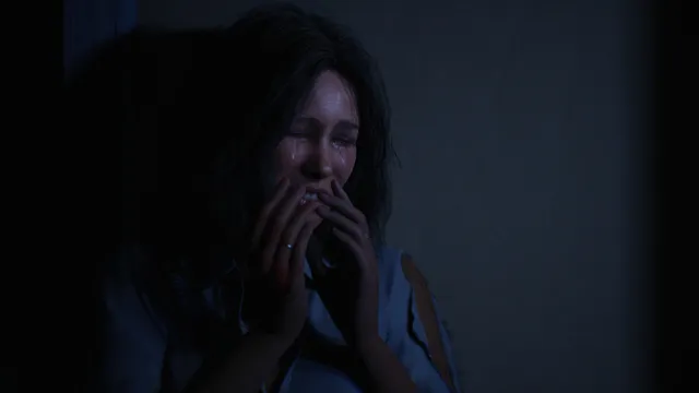 Halloween: The Game screenshot: a terrified woman covers her mouth in the dark, crying