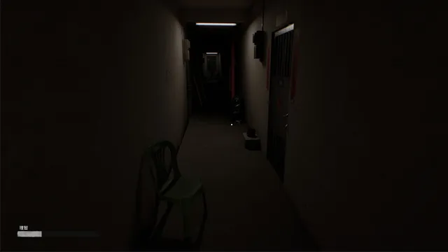 A narrow dark hallway outside the apartment with a green plastic chair and a single strip light at the far end