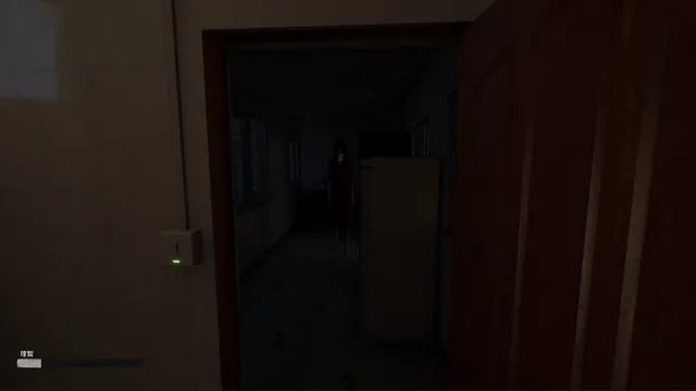A pale figure with long black hair standing in a dark room beyond an open red door