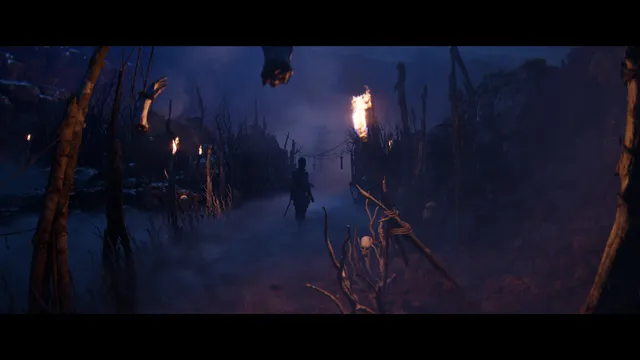 Hellblade II: Senua's Saga screenshot: a misty path through a camp of stakes and torches hung with bones, a figure walking ahead