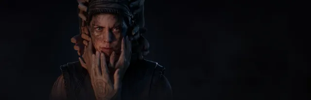Hellblade II: Senua's Saga key art: Senua's grim, dirt-streaked face surrounded by many hands reaching from the darkness to touch her head