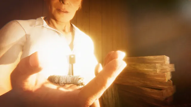 Hollow Cocoon screenshot: a woman in a white blouse holds a silkworm cocoon in her open hand, a key on a cord around her neck