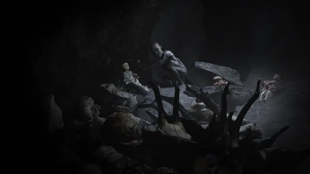 A dark cave strewn with broken dolls and twisted roots around a pale figure