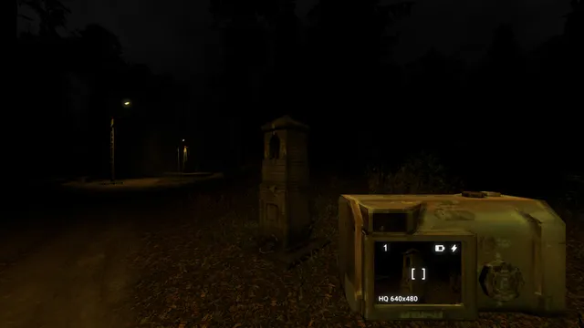Krypta FM: a roadside shrine on a dark forest road at night, seen through the screen of a chunky handheld digital camera