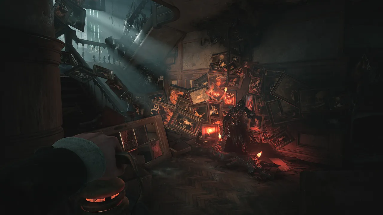 Layers of Fear screenshot: a first-person hand holds up a glowing lantern before a mansion staircase buried under a heap of framed paintings, with a dark figure in the glow