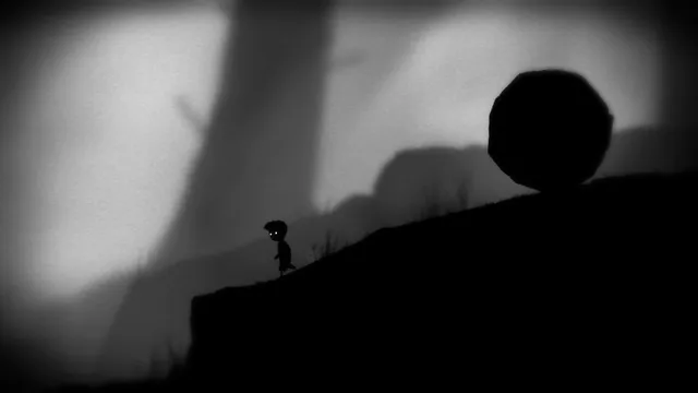 A huge round boulder sits at the top of a dark slope above the boy in the misty forest