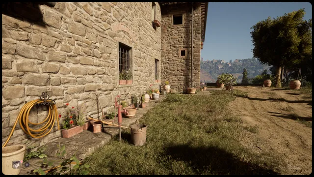 Martha Is Dead screenshot: the stone wall of a Tuscan farmhouse with flower pots and a garden hose, a hill town in the distance under blue sky