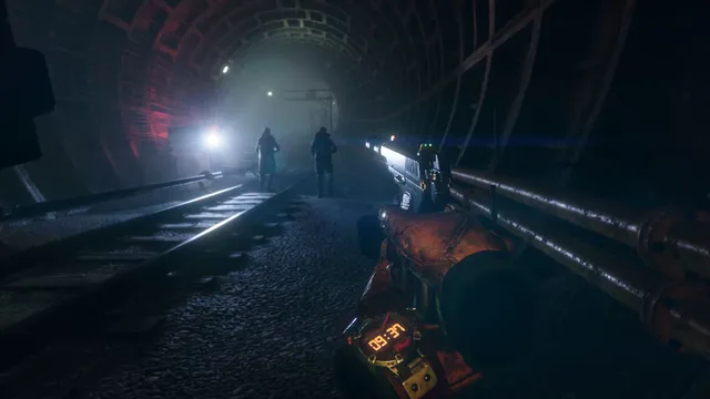 The player aims a pistol down a dark metro tunnel at two figures approaching along the tracks