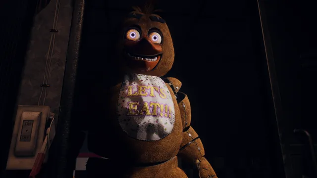 A lifelike Chica with a Let's Eat bib standing in the dark office doorway