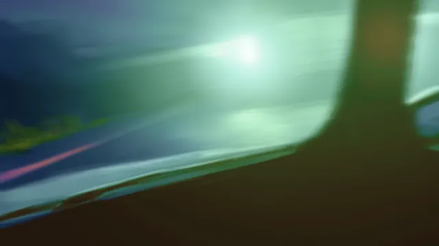 Night Drive screenshot: a blurred view out of the car's side window, green light streaking past the night road