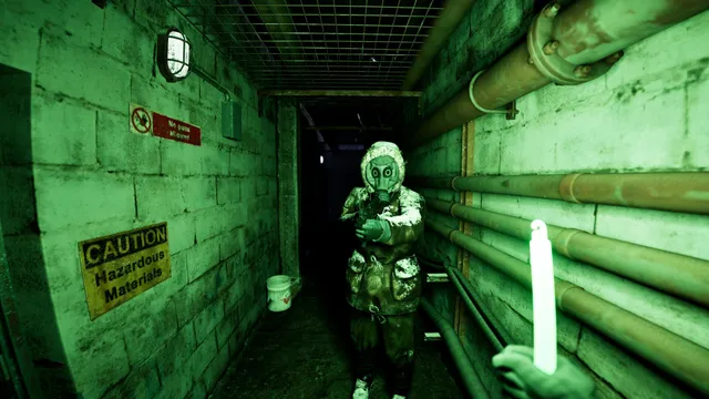 A figure in a filthy gas mask and hood stands in a green-lit tunnel with a caution sign, a candle held up in the foreground
