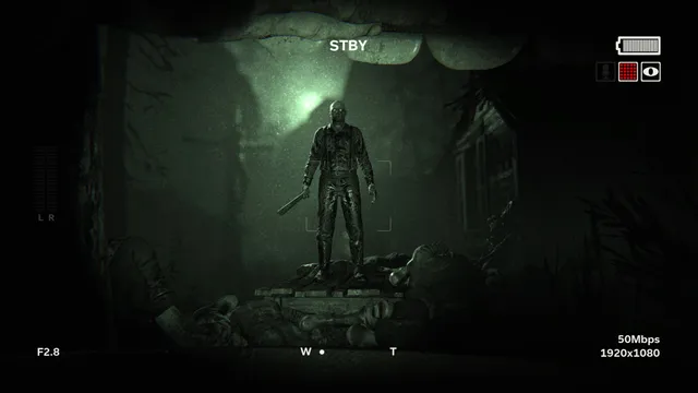 Outlast 2 screenshot: through the camcorder's viewfinder, a man holding a machete stands over bodies in a green-lit cave