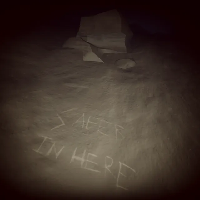 Words scratched into the rock of the cave floor: SAFER IN HERE