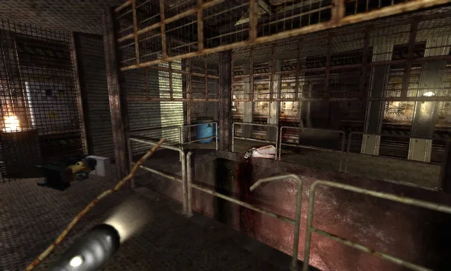 Penumbra: Black Plague screenshot: a flashlight lights rusty railings and cages in a dim industrial room