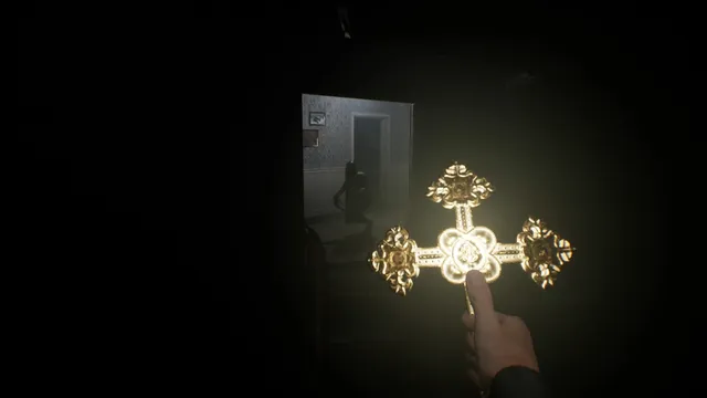 A hand holds up a glowing gold cross in a dark room while a shadowy figure stands in the doorway behind