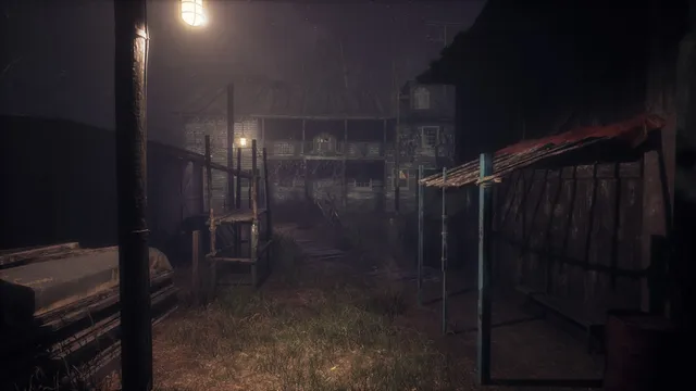 The wooden mansion at night seen across its overgrown yard under a street lamp