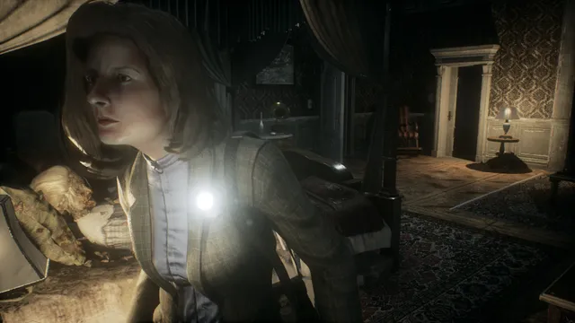 Remothered: Tormented Fathers screenshot: Rosemary crouches by a bed with a torch pinned to her jacket, a doorway into a lamp-lit room behind