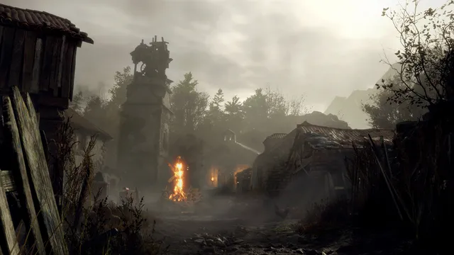 Resident Evil 4 screenshot: a foggy run-down village with a stone clock tower, a bonfire and tiled-roof houses