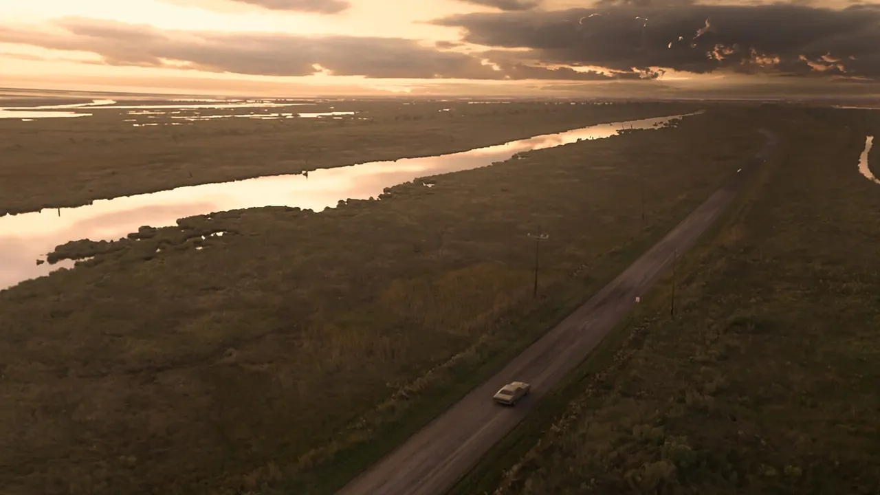 Resident Evil 7 screenshot: an aerial view of a car on a lone road through the Louisiana bayou at dusk