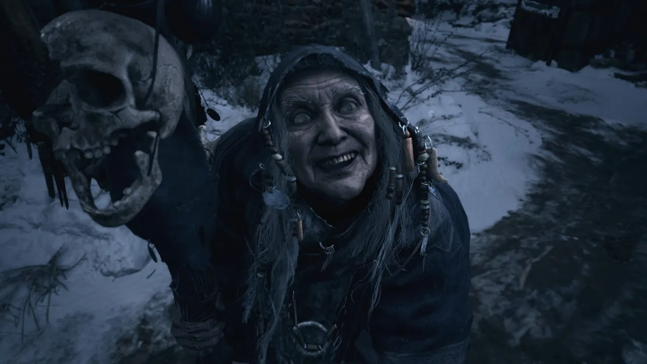 Resident Evil Village screenshot: an old woman in a hooded cloak leans close and grins, holding a skull on a staff in the snow