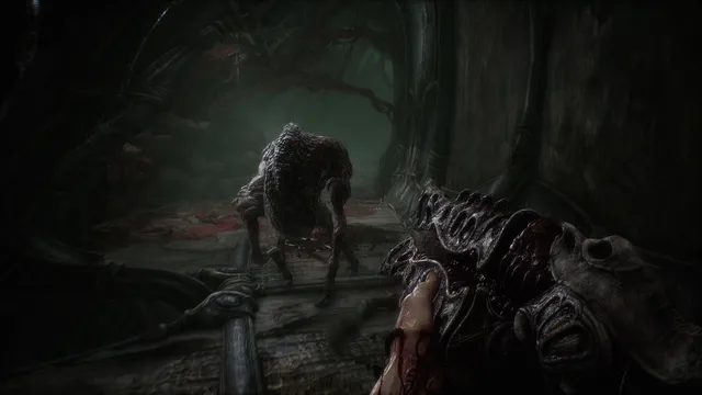 Scorn screenshot: a first-person hand holds a fleshy organic weapon as a hunched, skinless creature advances down a blood-smeared corridor