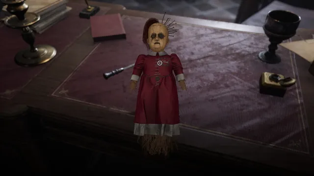 A doll in a red dress stuck with pins, on a desk